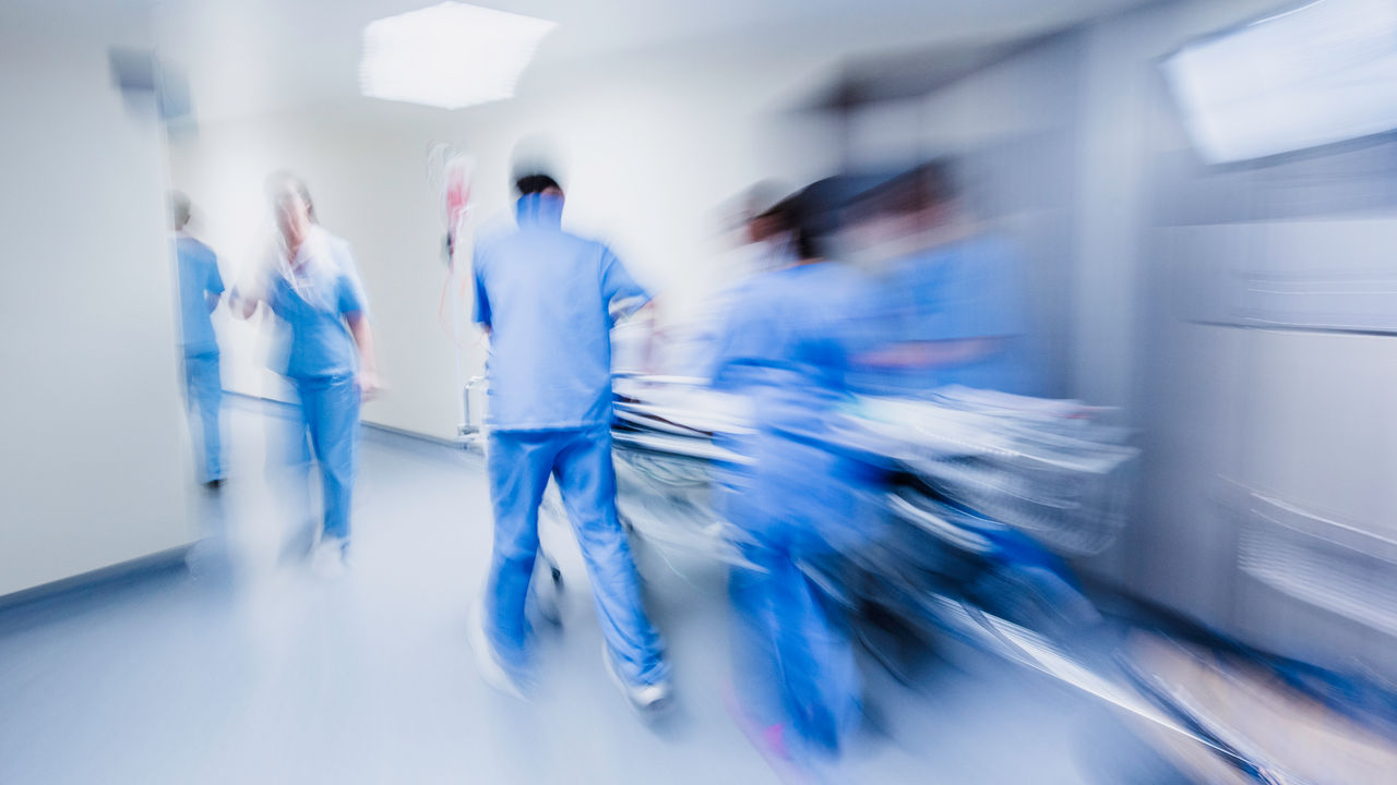 Doctors and nurses pulling hospital gurney through a hallway, blurred