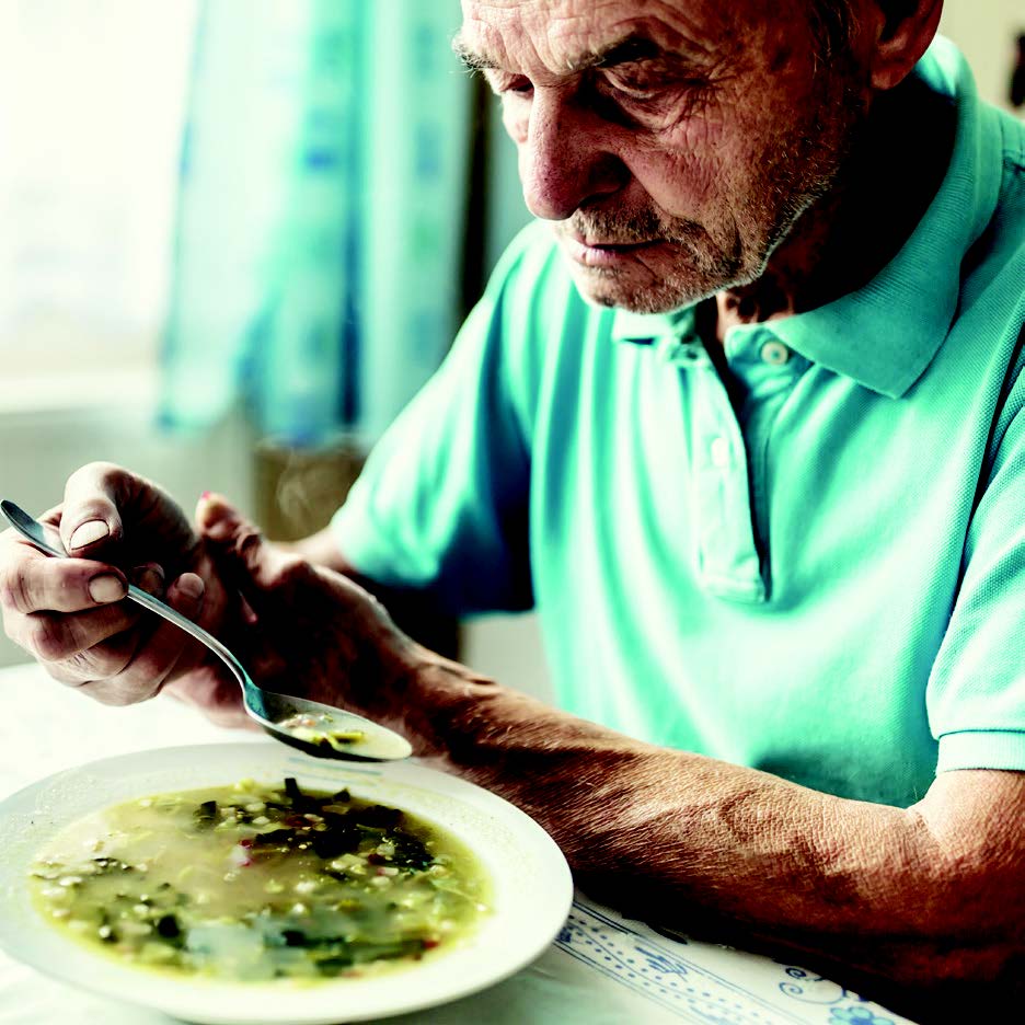 A senior man eating a bowl of soup