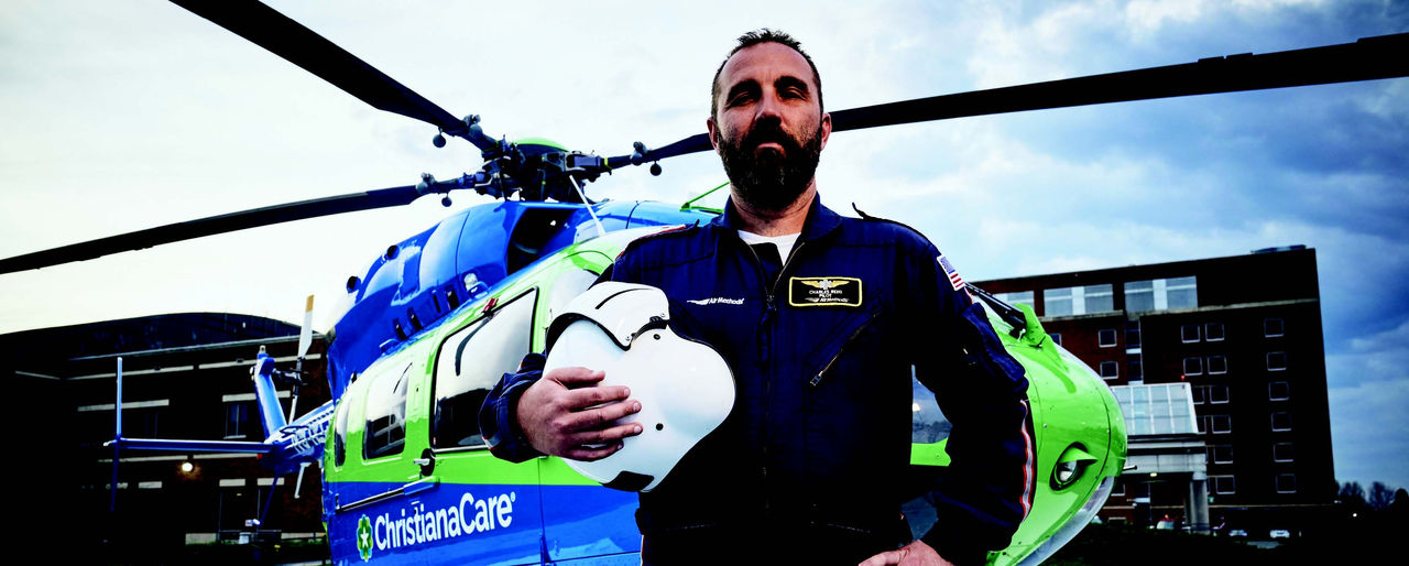 ChristianaCare's LifeNet medical transport helicopter, with its pilot standing in front of it