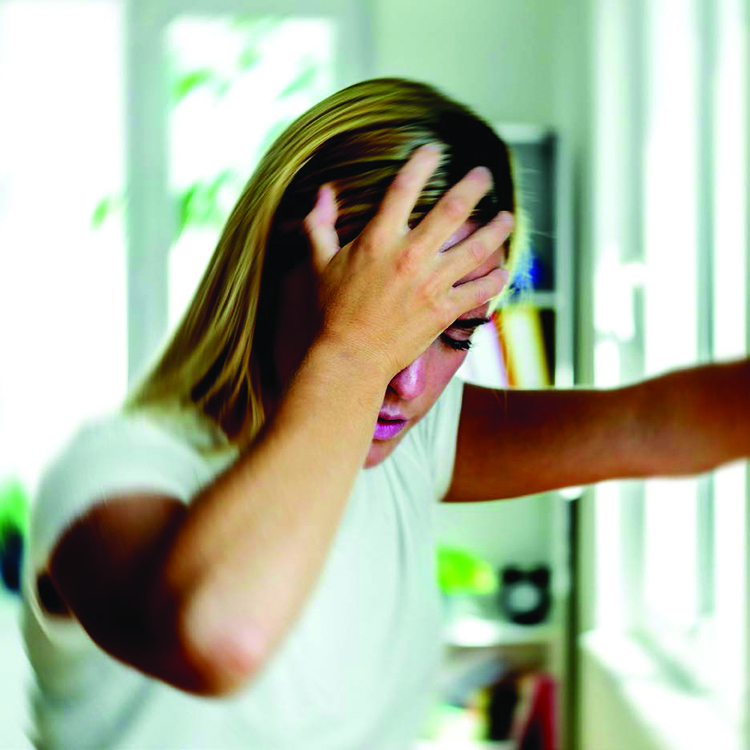 A young woman holds her head in pain