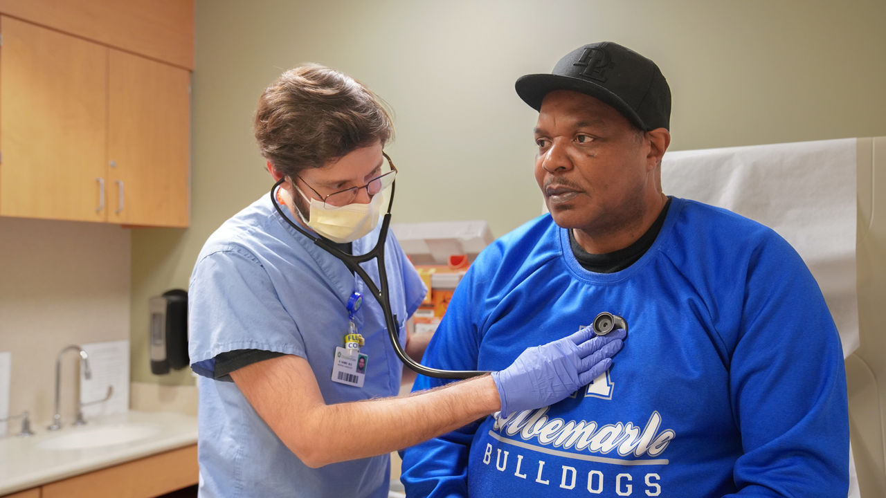 A doctor uses a stethoscope to listen to a man's heart