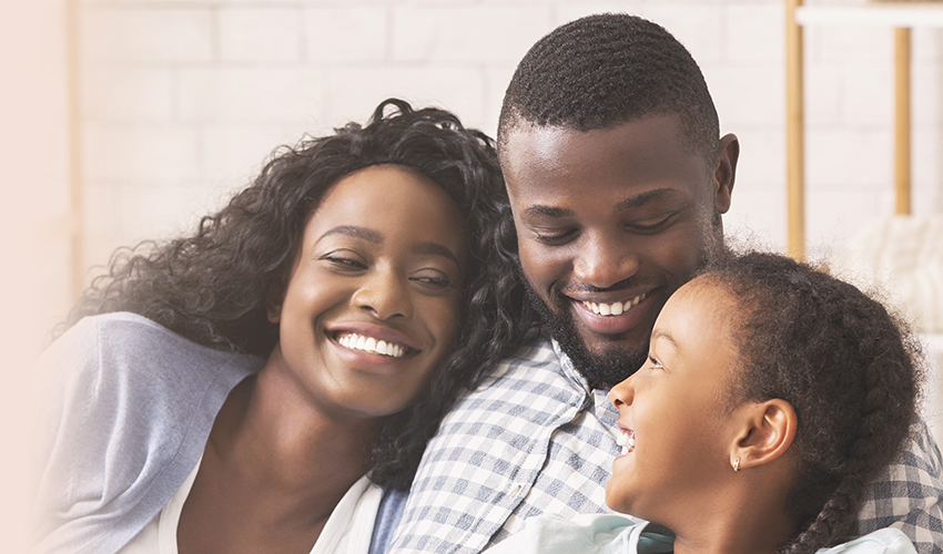 Familia afroamericana sonriente relajándose en el sofá y viendo televisión en casa, hombre cambiando de canales