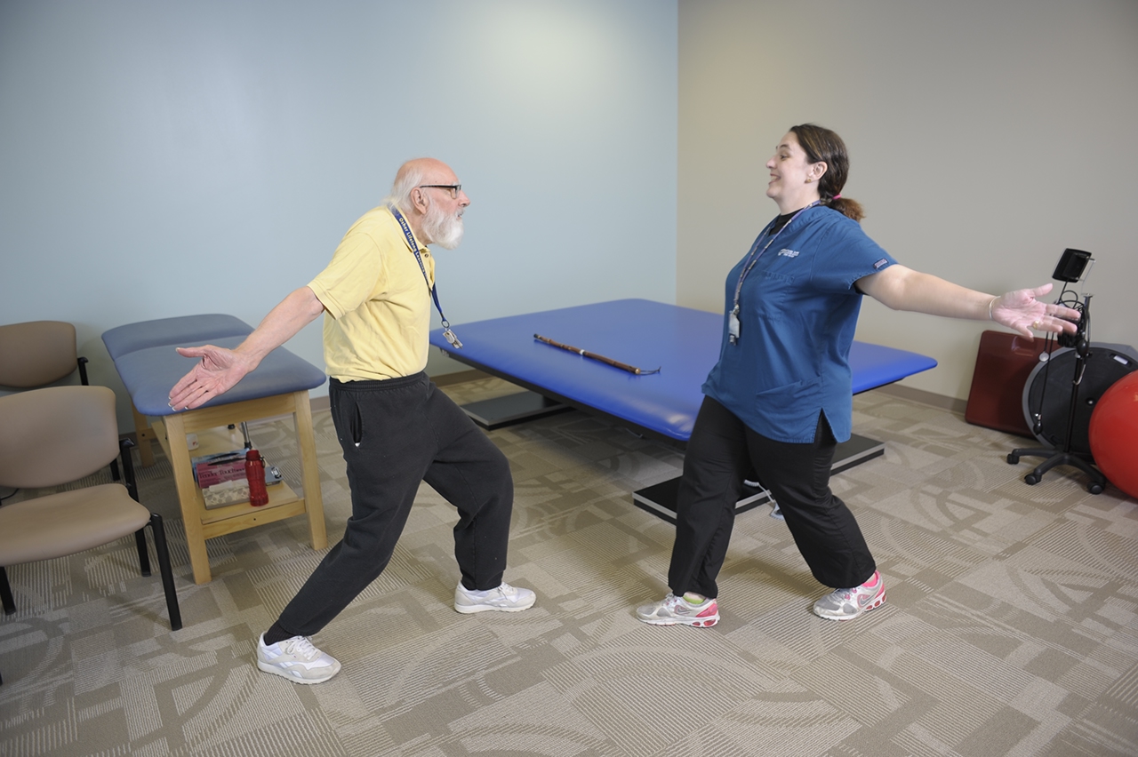 Un terapeuta que orienta a un paciente que tiene Parkinson con ejercicios de la terapia LSVT BIG