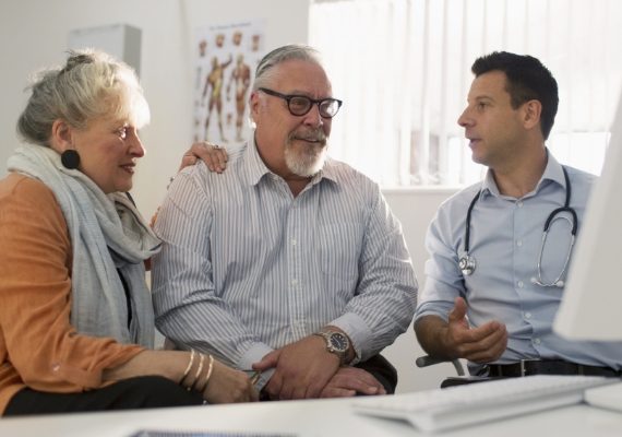 Doctor meeting with senior couple at computer in doctors office