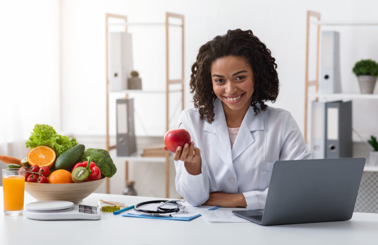 Una asesora de salud que sostiene una manzana