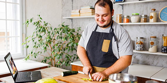 Un hombre que está contento y cocina comida saludable en la cocina